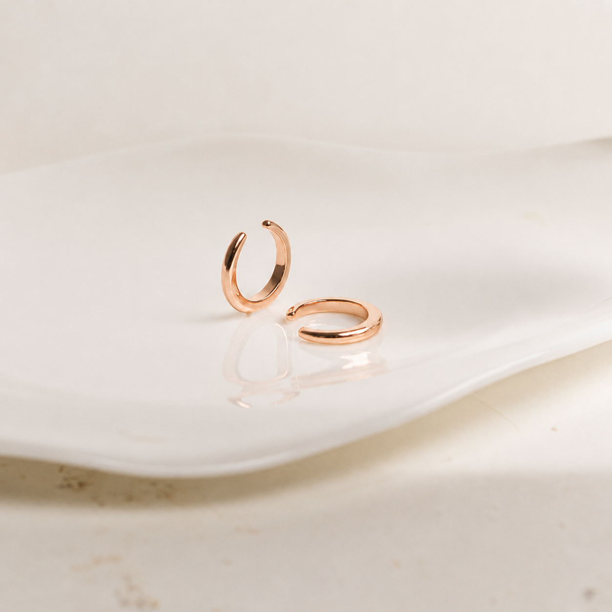 Rose gold hoop earrings on a light beige surface